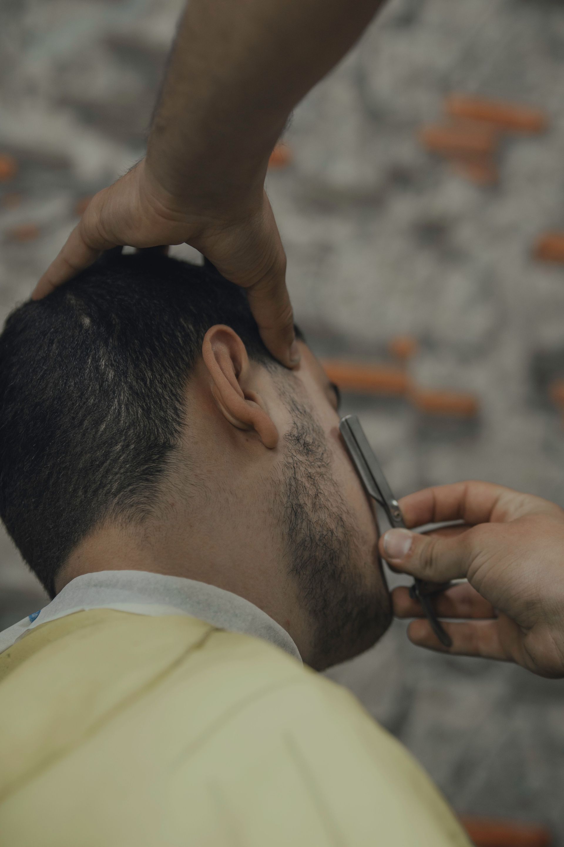 A man getting a close shave with a straight razor at a barbershop.